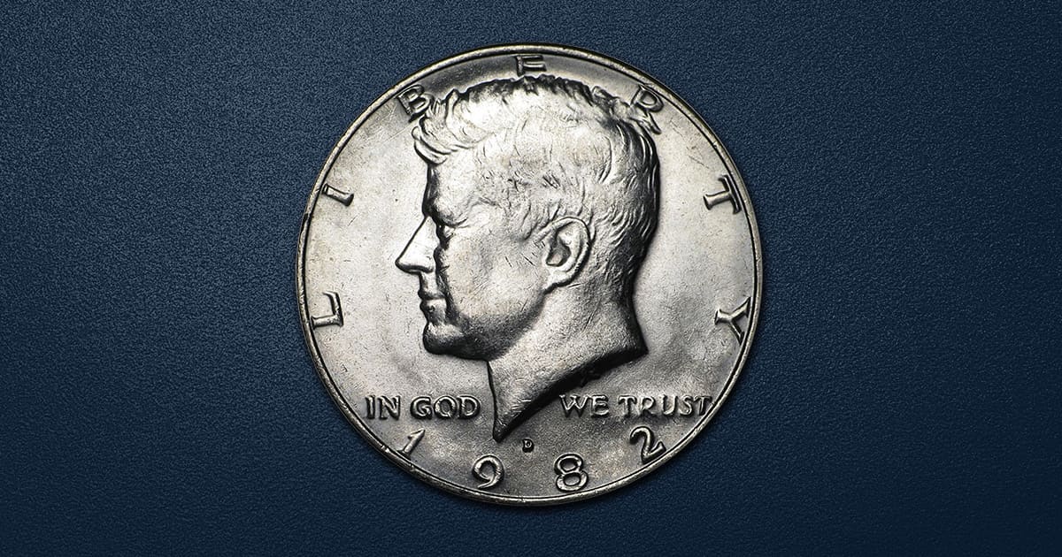 Grading strip showing four 1982 Kennedy half dollars in four grades: worn (G), XF, MS63, and MS65 gem uncirculated